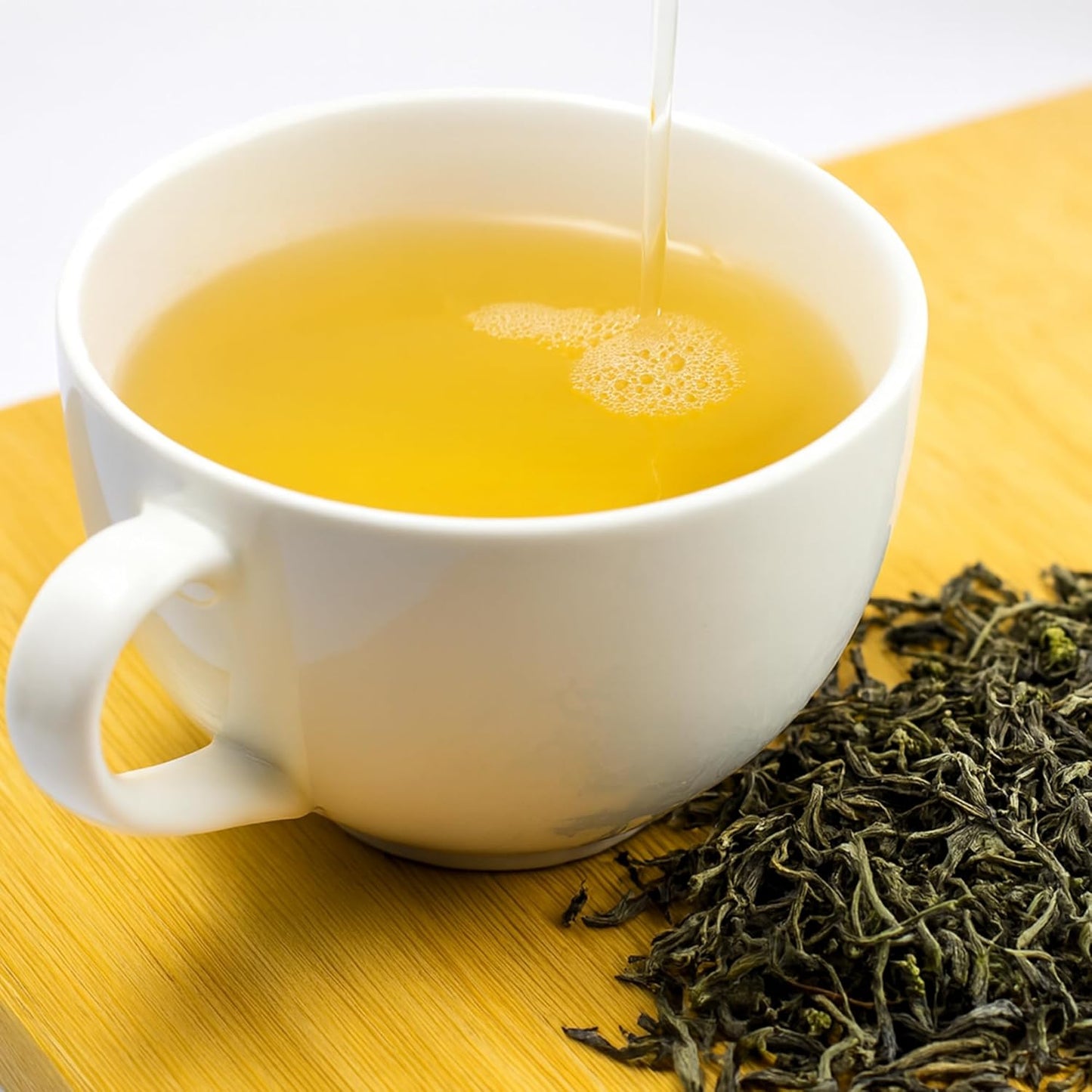 Cup of green tea served hot with Happy Valley green tea tin.